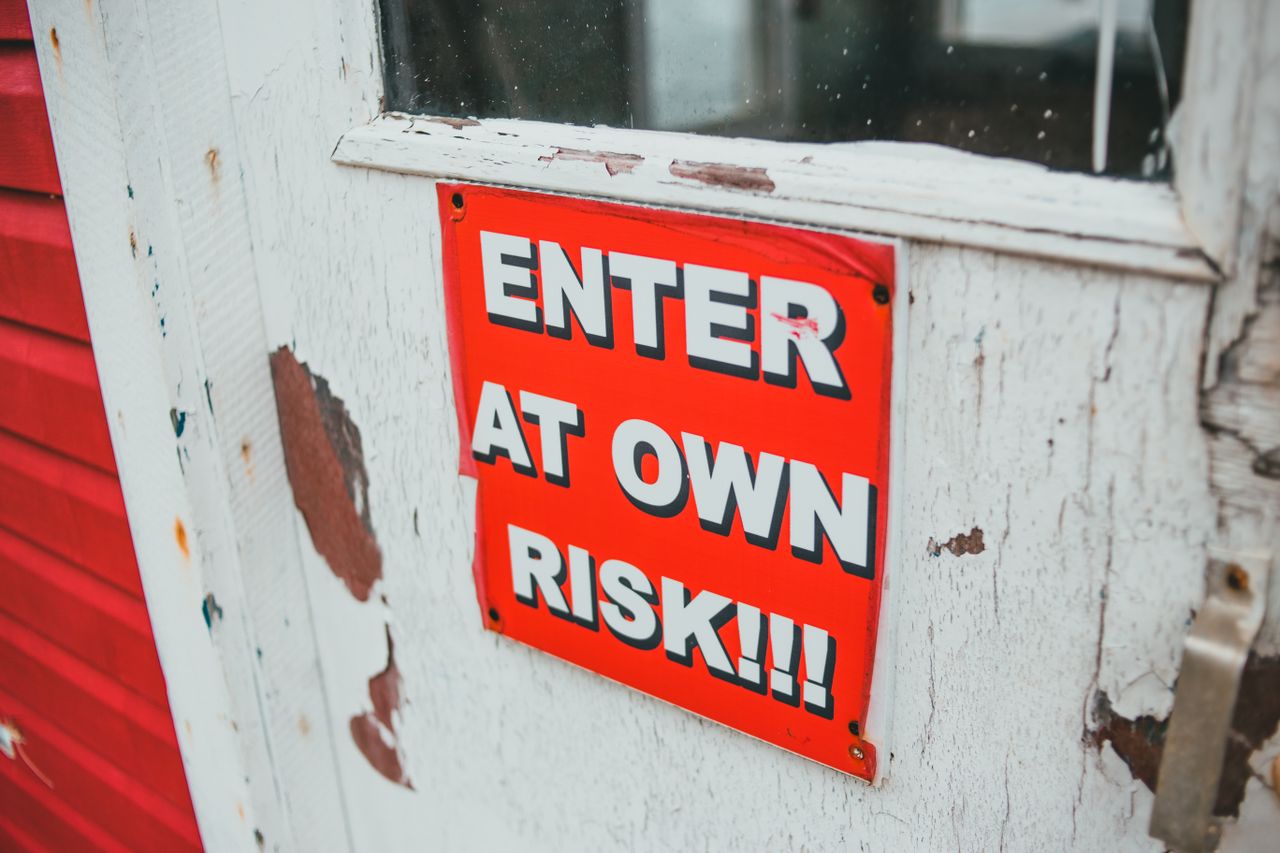 Close-up of a bright red warning sign on a weathered wooden door.